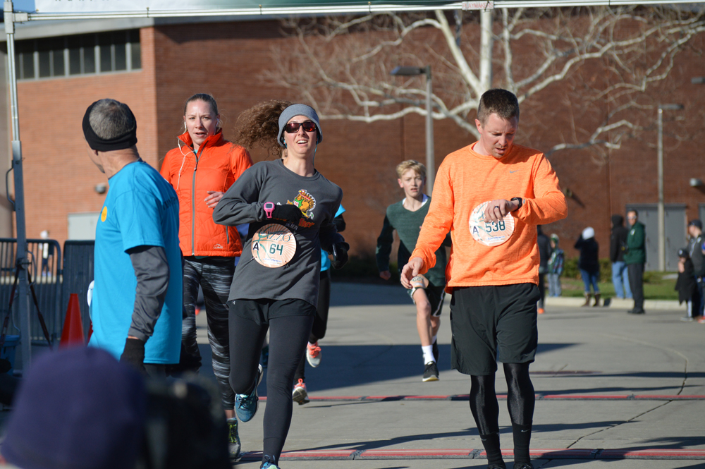 Dr. Julie Krupa (orange jacket) crosses the 5K finish line